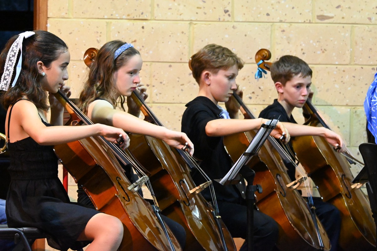 Orchestra on stage taking a bow after performance, pipe organ in the background.